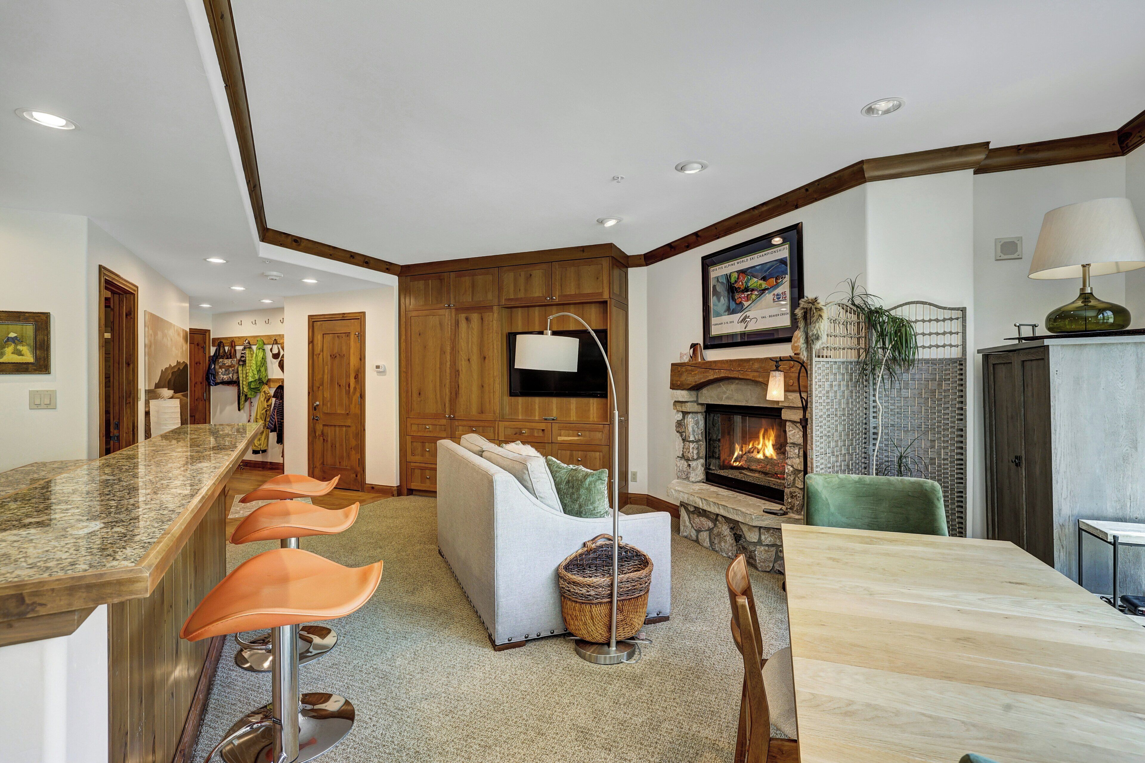 A modern kitchen with a bar area, a fireplace, and a seating area with a sofa and chairs.