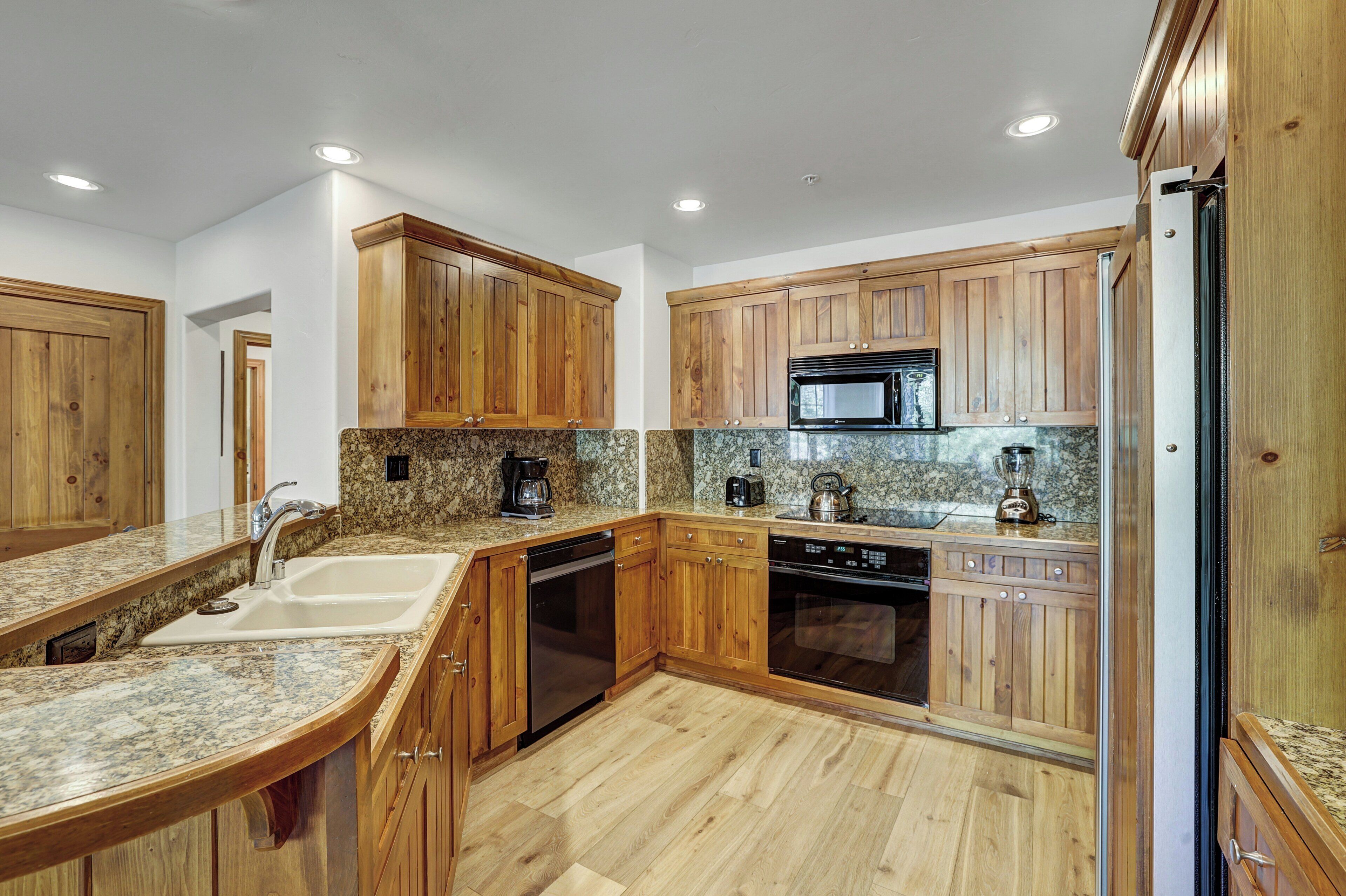 A kitchen with wooden cabinets, granite countertops, a microwave, and a dishwasher.