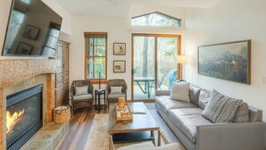 A living room with a fireplace, a sofa, a coffee table, and a dining area with chairs. - Lodge at Brookside, A Vail Resorts Property (Avon)