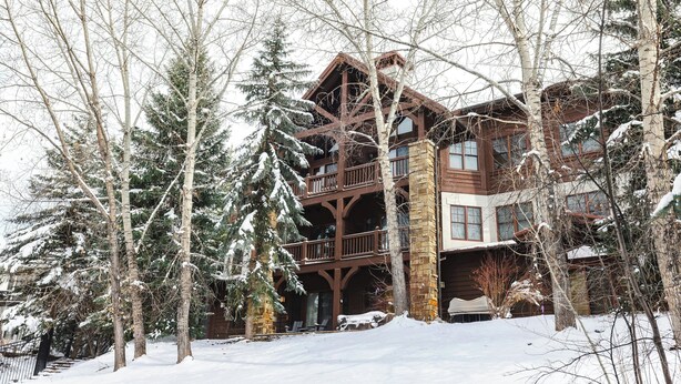 A multi-story lodge with a wooden exterior and stone accents, surrounded by snow-covered trees. - Lodge at Brookside, A Vail Resorts Property (Avon)