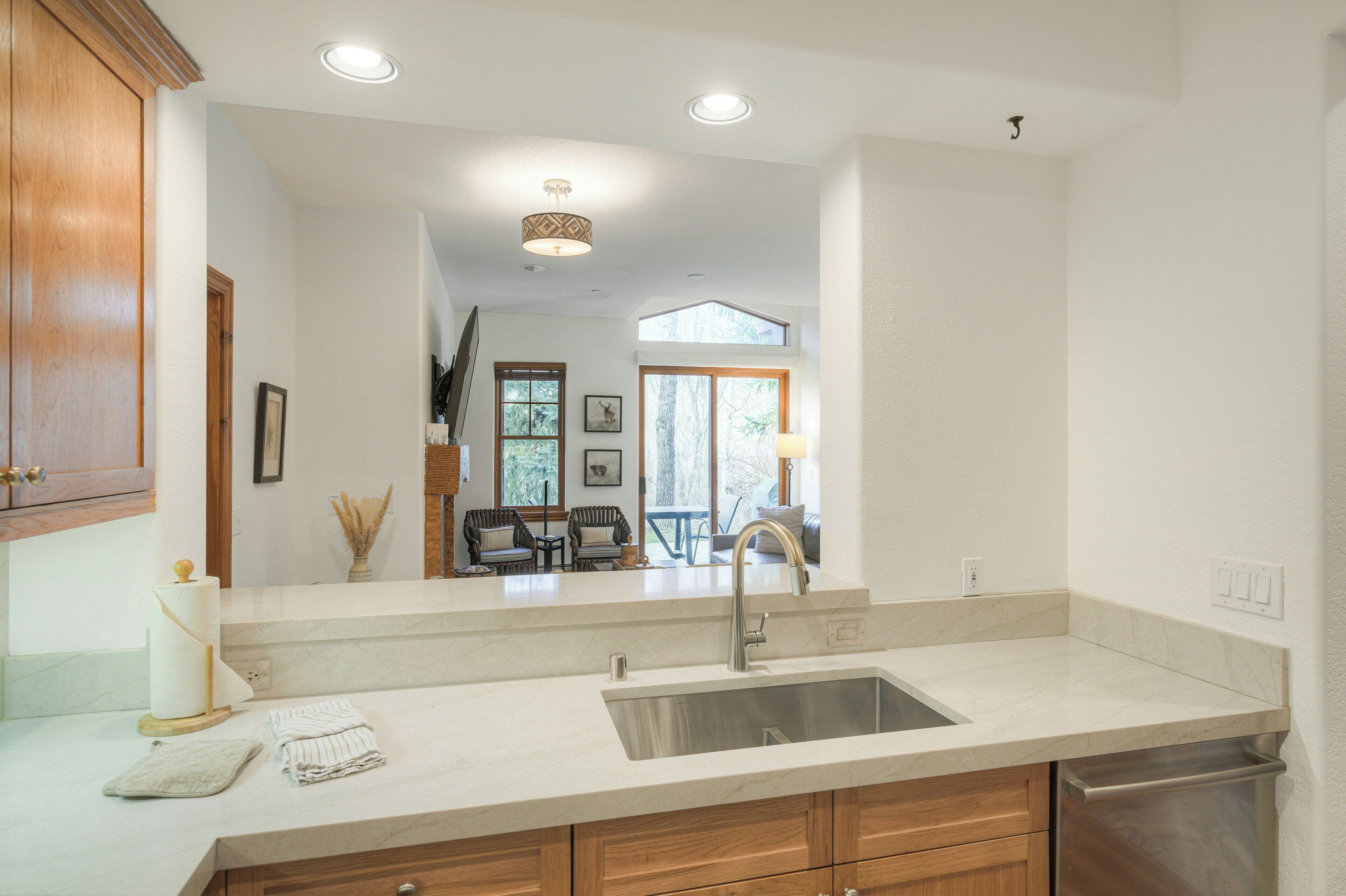A kitchen with a large sink, wooden cabinets, and a view into a dining area.