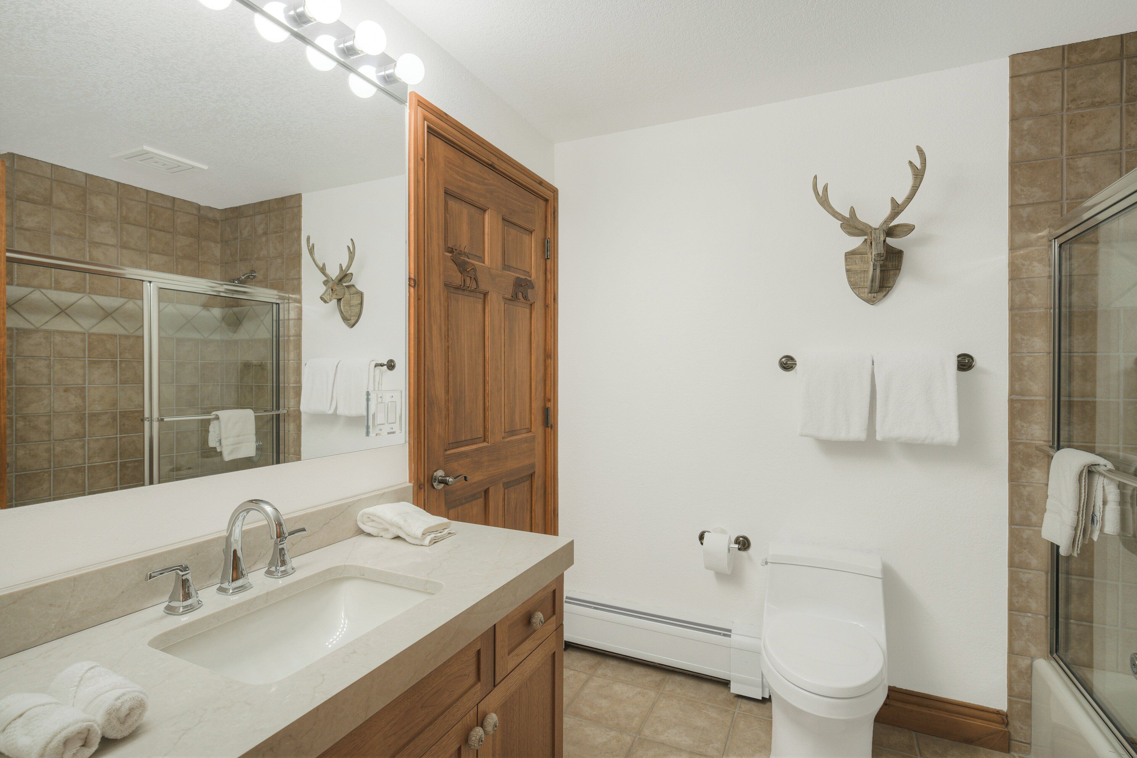 Une salle de bain avec un grand miroir, un lavabo, des toilettes et une douche.