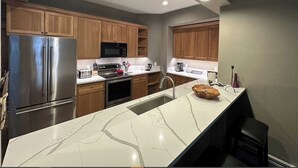 A modern kitchen with wooden cabinets, stainless steel appliances, and a marble countertop. - Lodge at Brookside, A Vail Resorts Property (Avon)