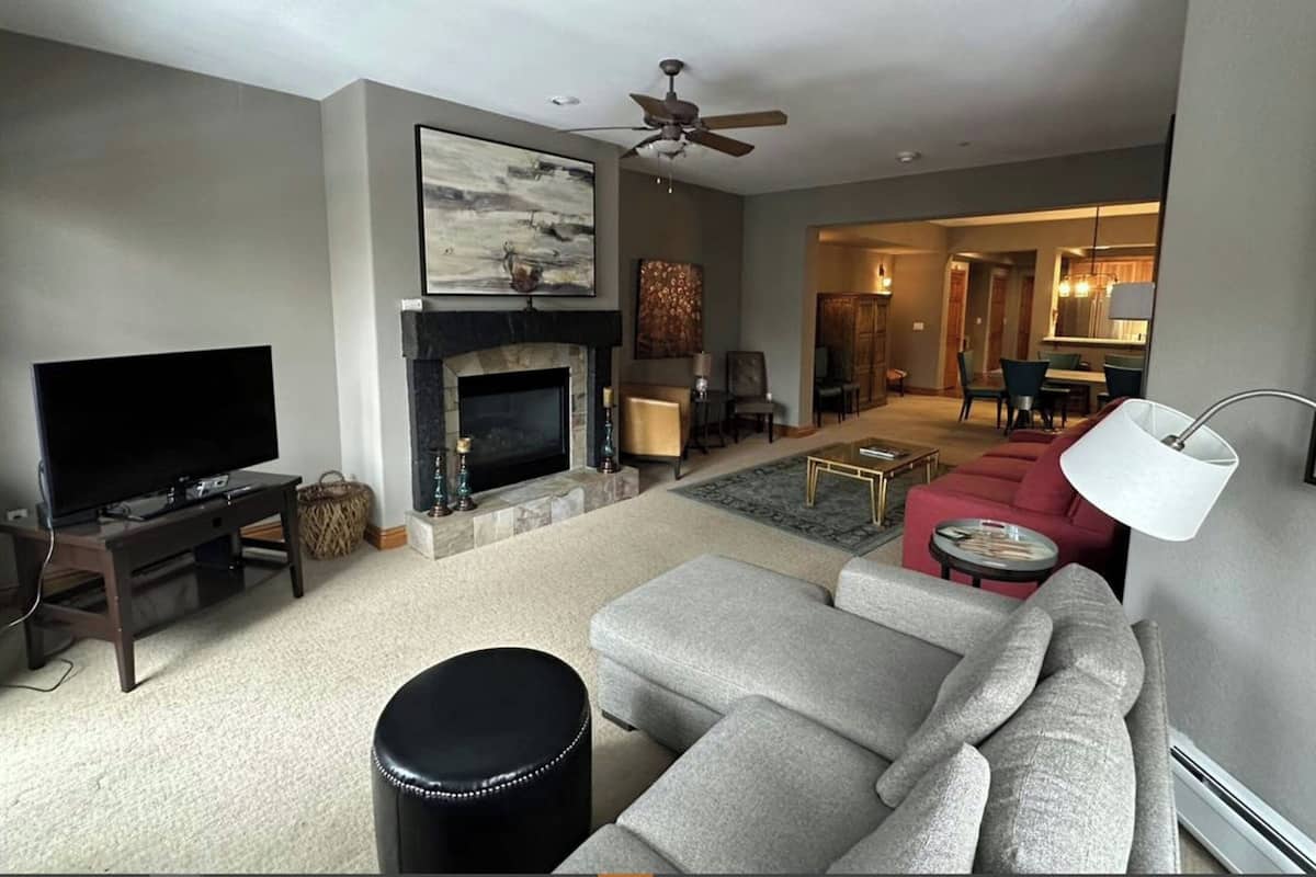 Una sala de estar con chimenea, televisor, sofá y ventilador de techo.