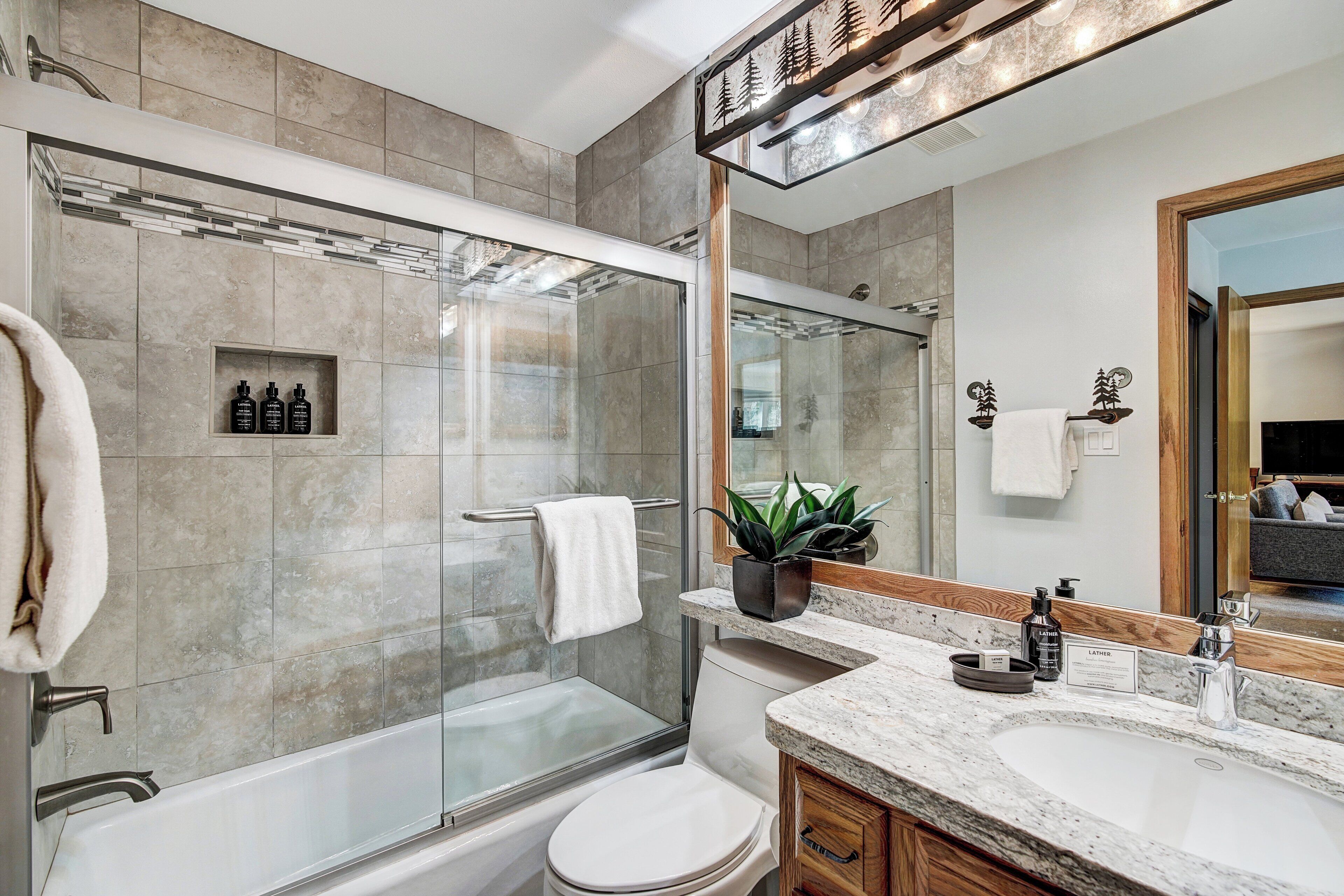 Une salle de bain moderne avec une douche à parois de verre, des toilettes et un meuble-lavabo doté d’un évier et d’un miroir.