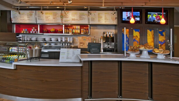 A modern cafe with a wooden counter, menu boards, and a coffee machine. - Courtyard by Marriott Newark Granville (Newark)