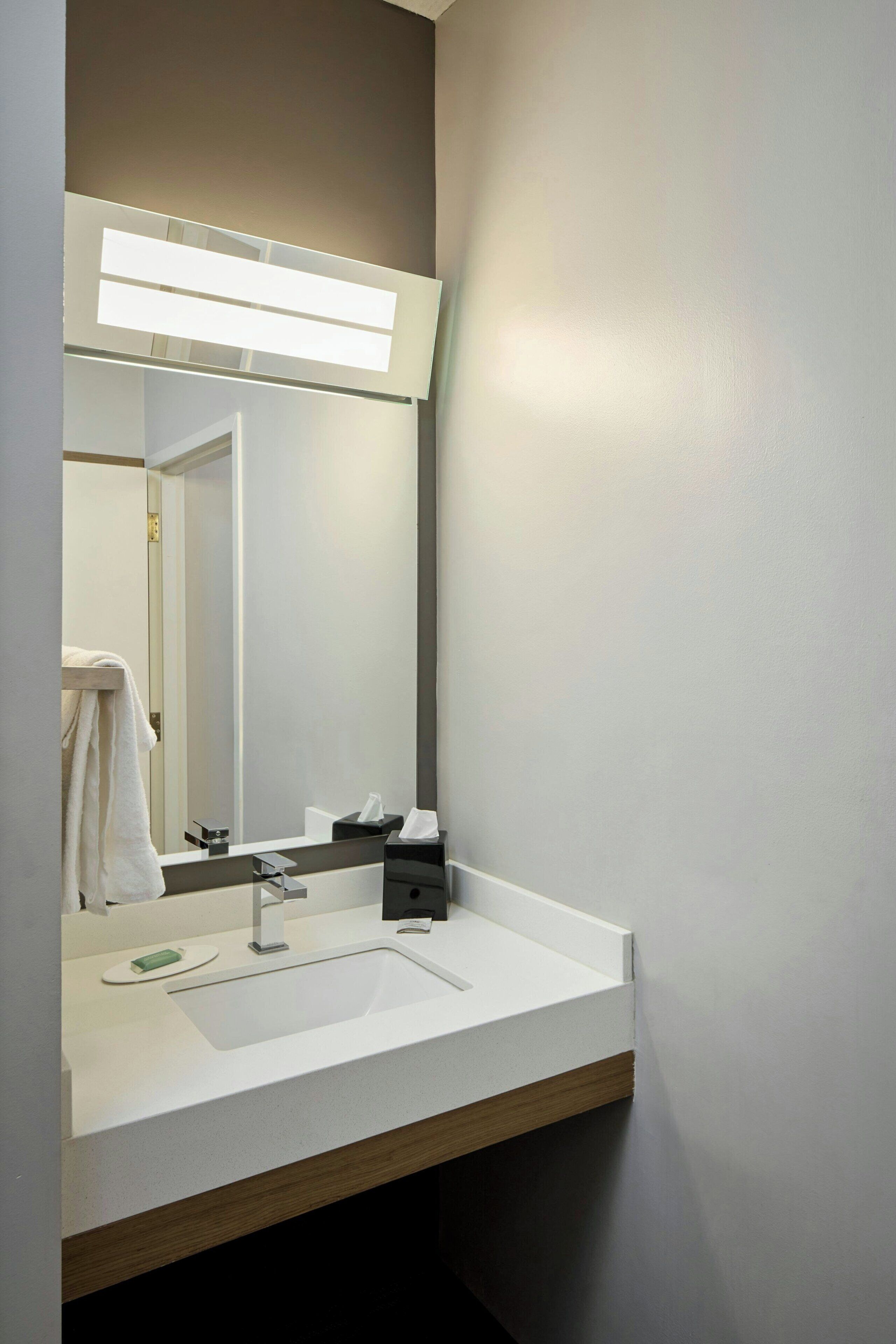 A modern bathroom with a white sink, a mirror, and a towel rack.