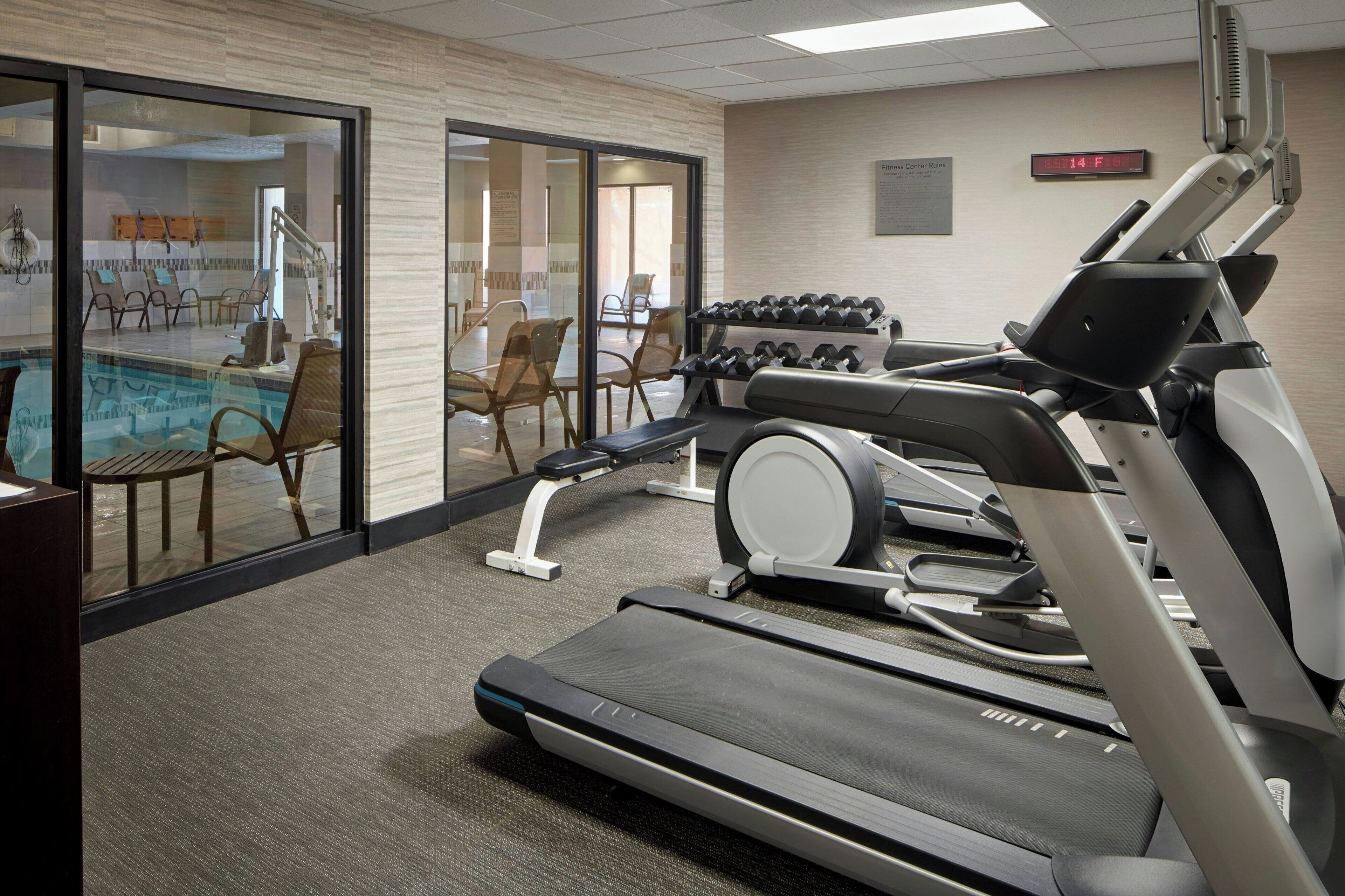 A gym with treadmills, dumbbells, and a pool area.