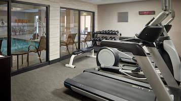 A gym with treadmills, dumbbells, and a pool area.