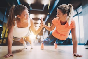 Two people in a gym doing push-ups.