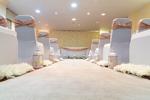 A carpeted aisle with white chairs and lanterns, leading to a stage with a floral backdrop. - Holiday Inn Rotherham Sheffield by IHG (Rotherham)