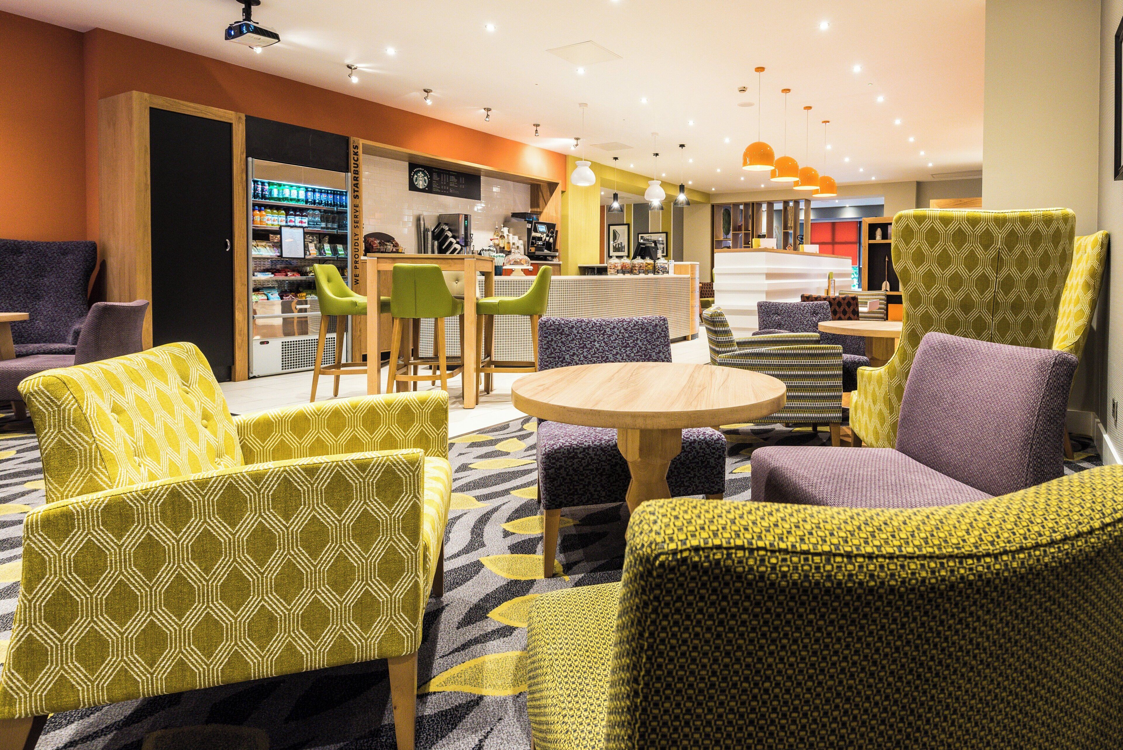Eine Hotelhalle mit Sitzbereichen, einem Starbucks-Stand und einer Rezeption.