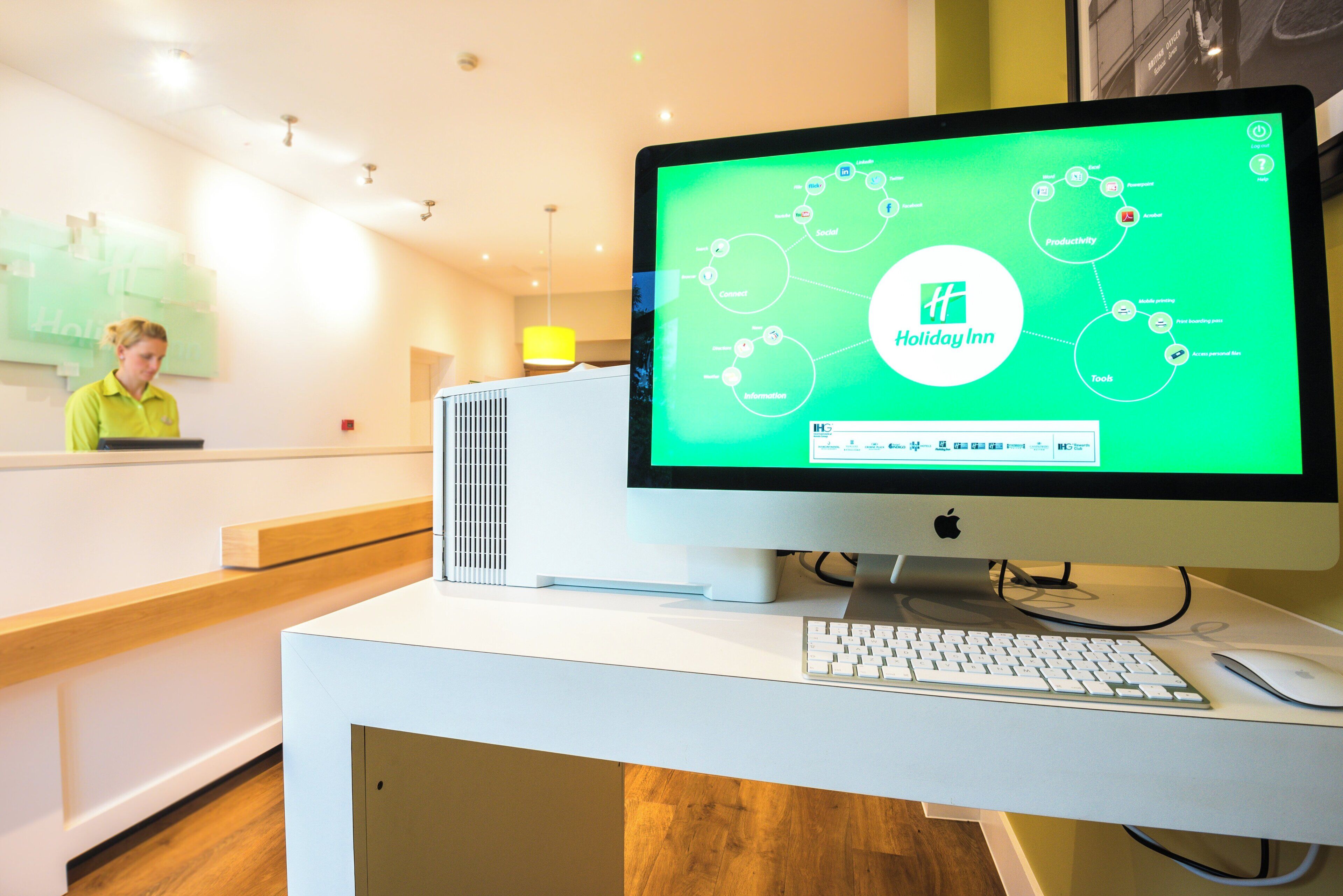 A desktop computer with a green screen displaying a Holiday Inn logo and various icons.