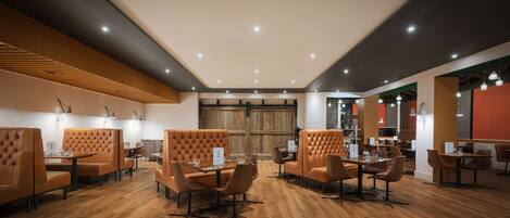 A modern restaurant interior with wooden flooring, leather booths, and pendant lighting.