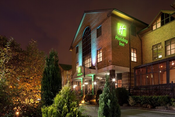 Experience the charm of this hotel's historic brick facade, featuring a grand arched window and beautifully maintained gardens.