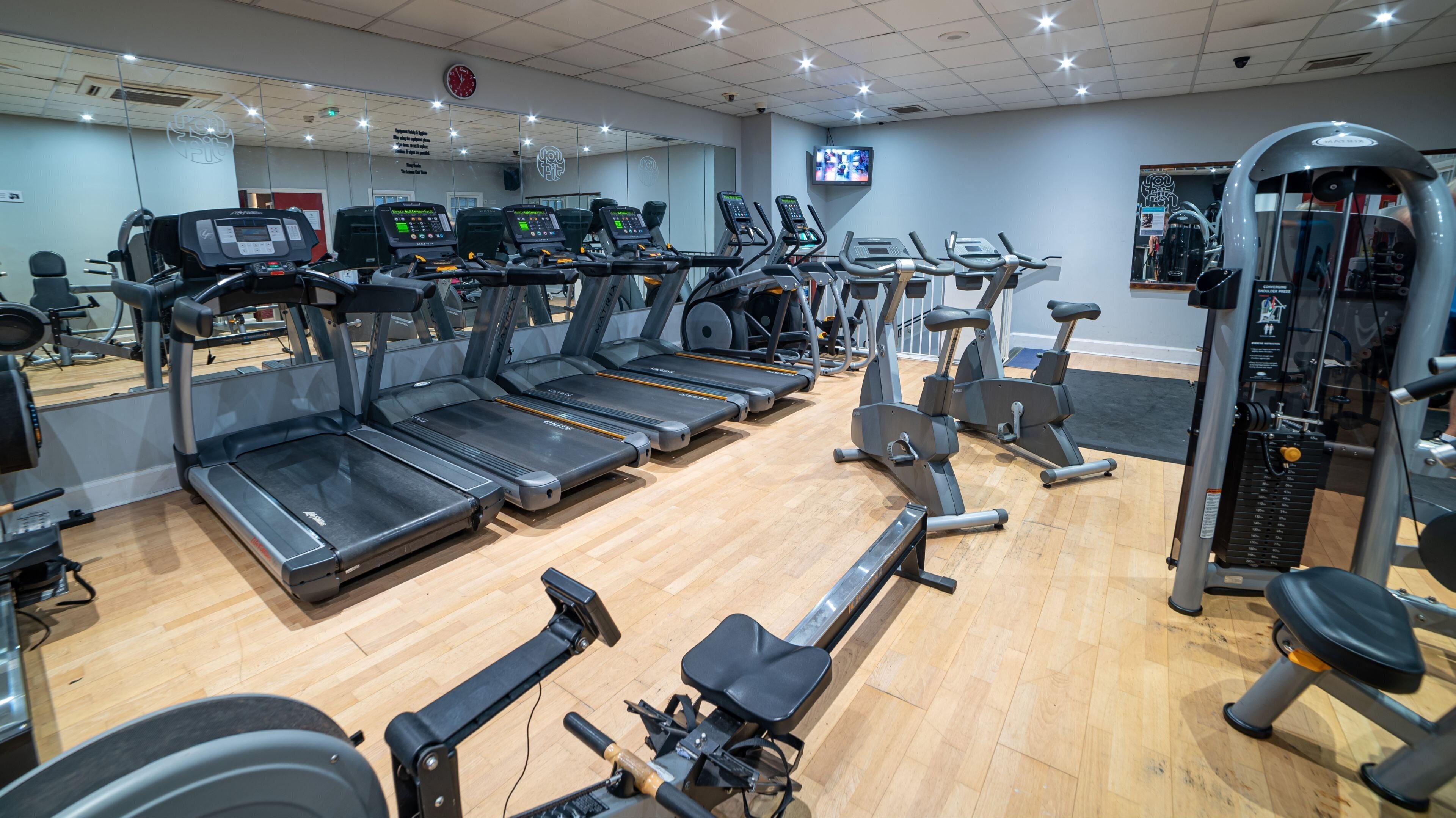 A gym with multiple treadmills, elliptical machines, and weight equipment.