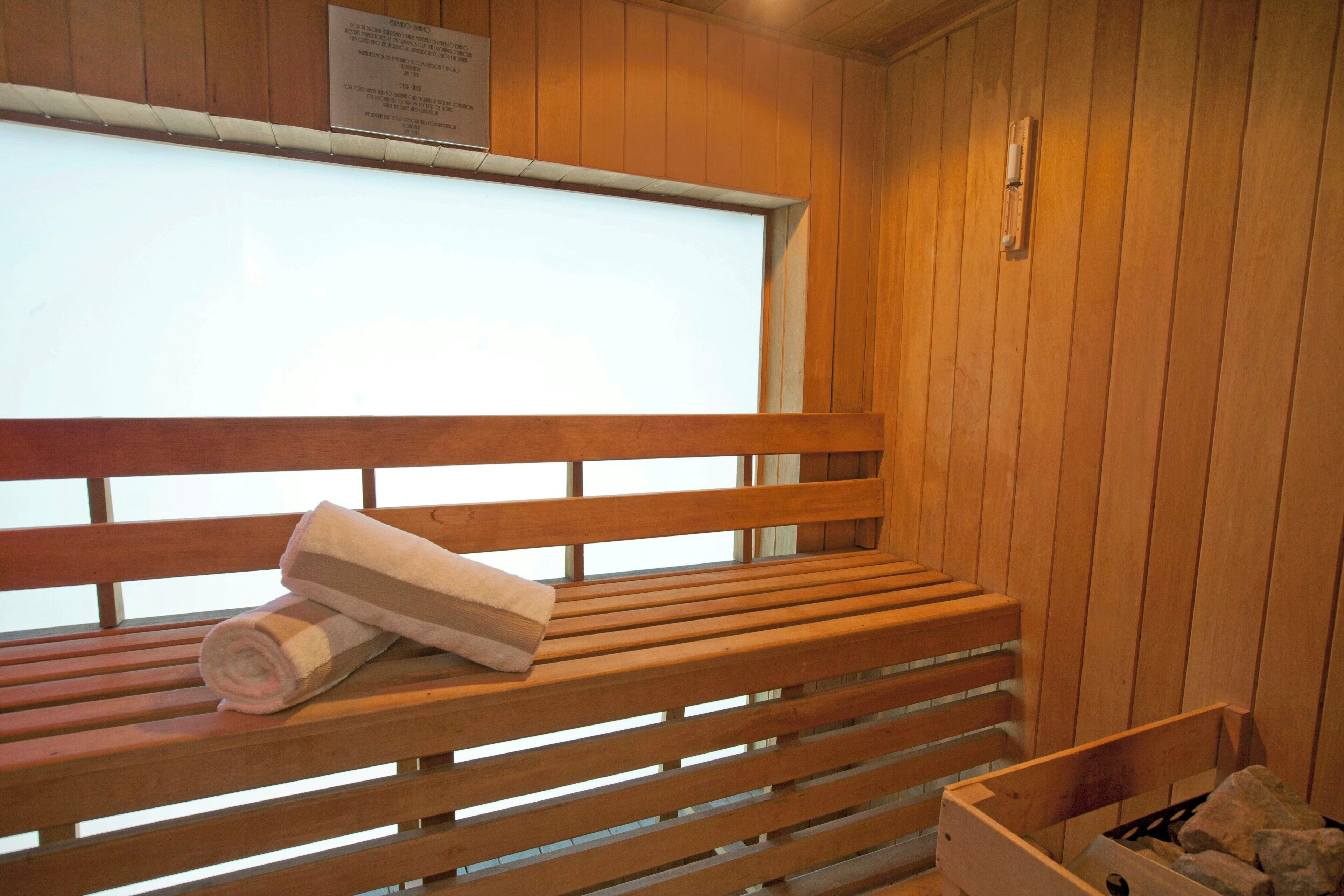 A wooden bench with towels, a window, and a wooden wall.