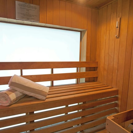 A wooden bench with towels, a window, and a wooden wall.