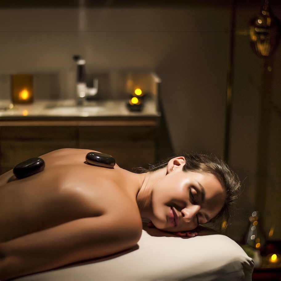 A person receiving a back massage with heated stones.