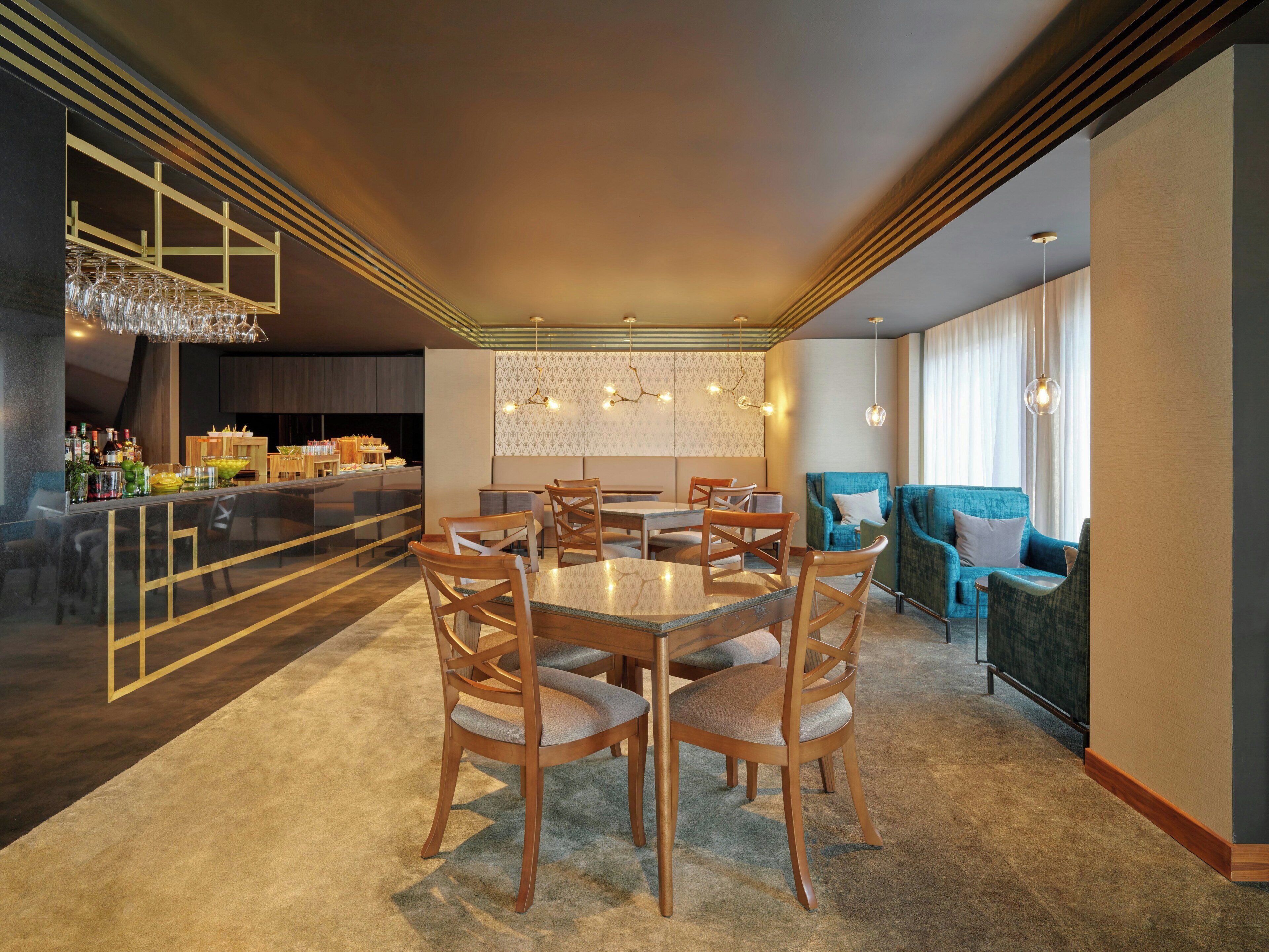 A modern dining area with a bar, wooden chairs, a glass-top table, and a patterned wall.