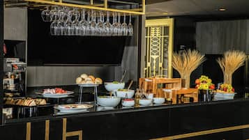 Una barra de buffet con diferentes opciones de comida, una máquina de café y un soporte para copas de vino.