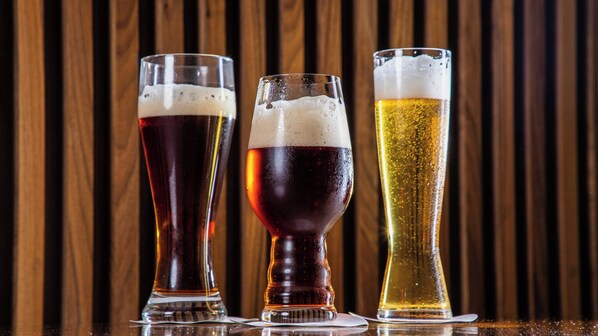 Tres vasos de cerveza sobre una barra con fondo de madera.