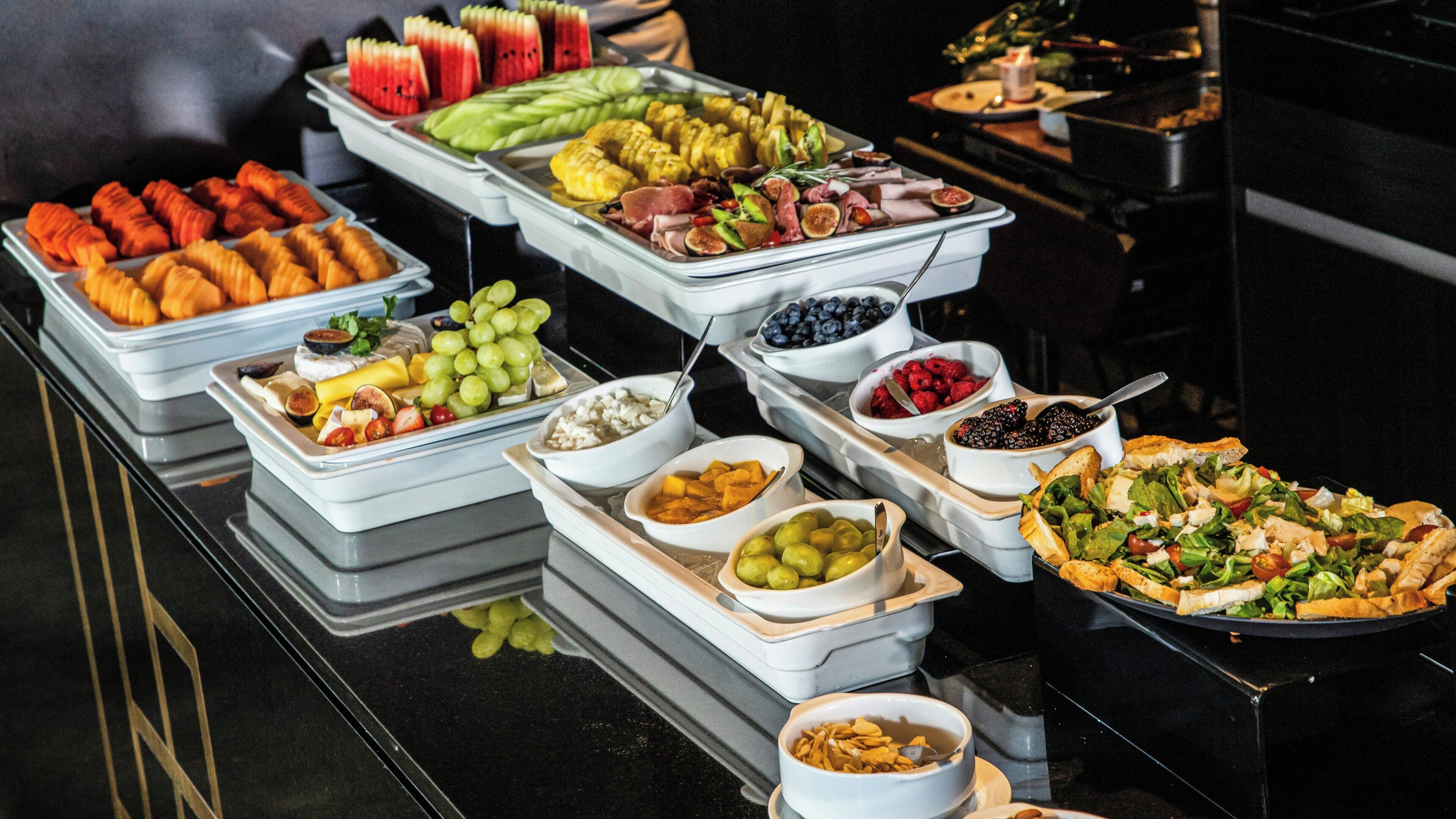 Un buffet proposant une variété de plats, notamment des fruits, des fromages et des salades.