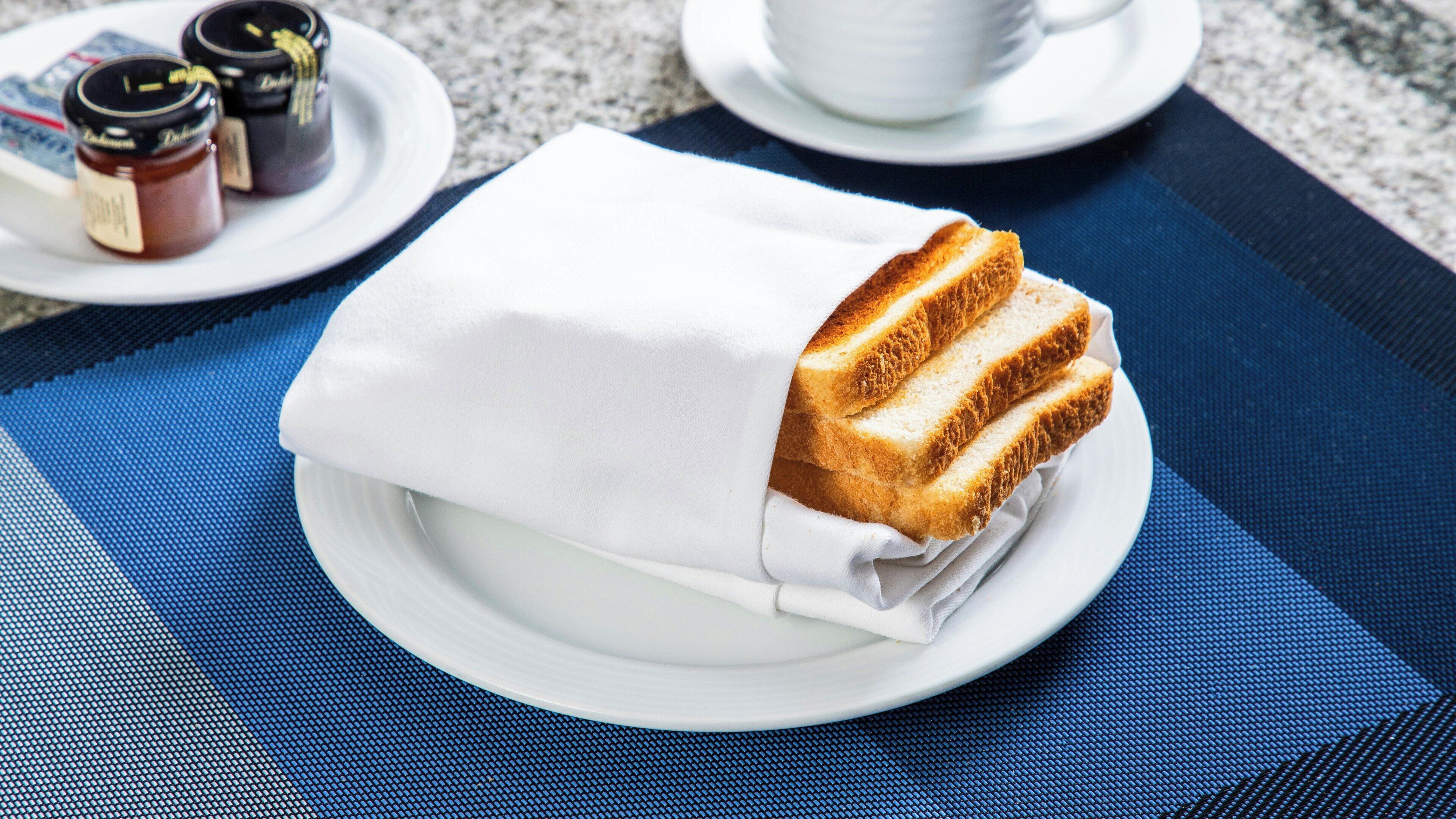 Ein Teller mit einem verpackten Sandwich auf einer blauen Tischmatte.