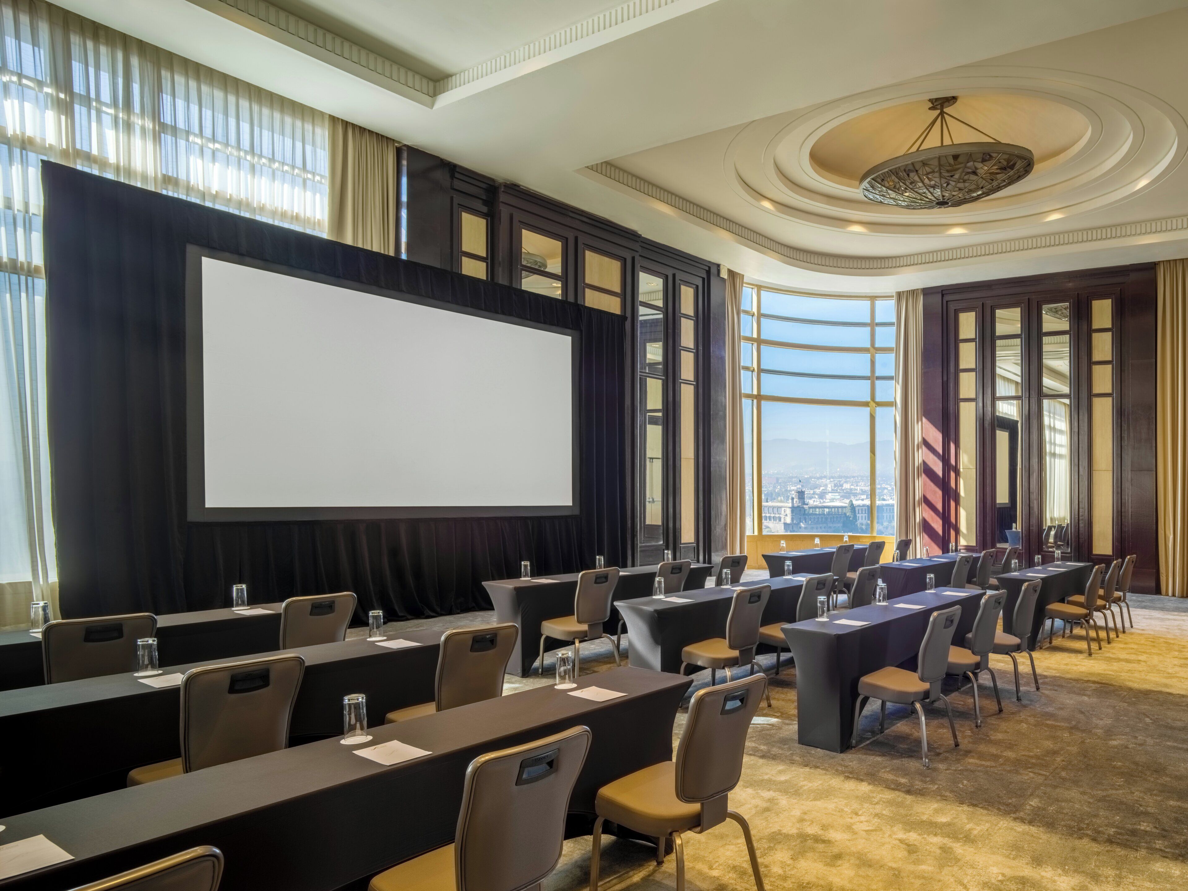 A conference room with a large screen, multiple tables, and chairs arranged for meetings.