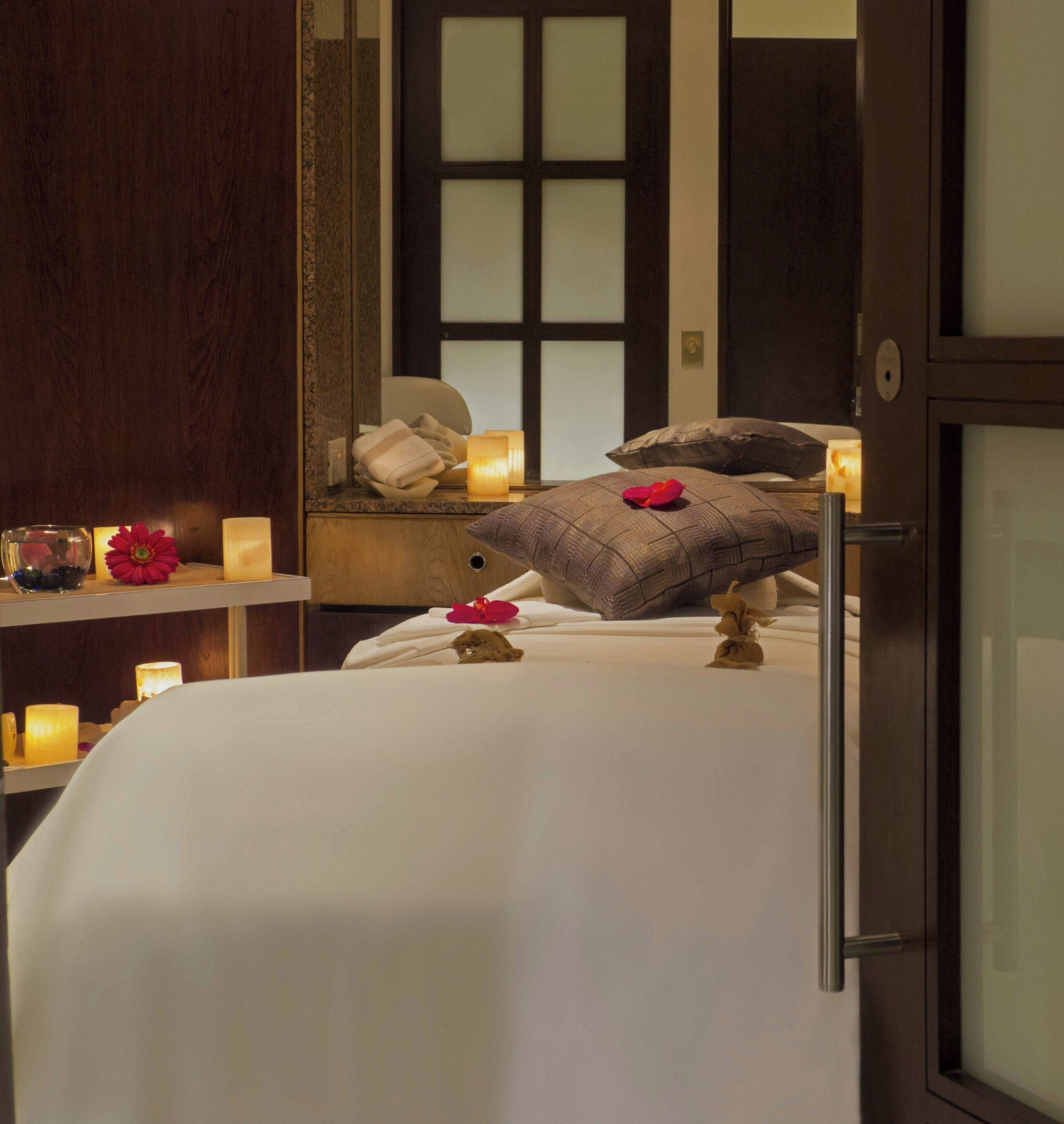 A bedroom with a bed, pillows, a nightstand, a mirror, and candles.