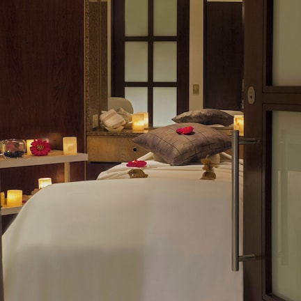 A bedroom with a bed, pillows, a nightstand, a mirror, and candles.