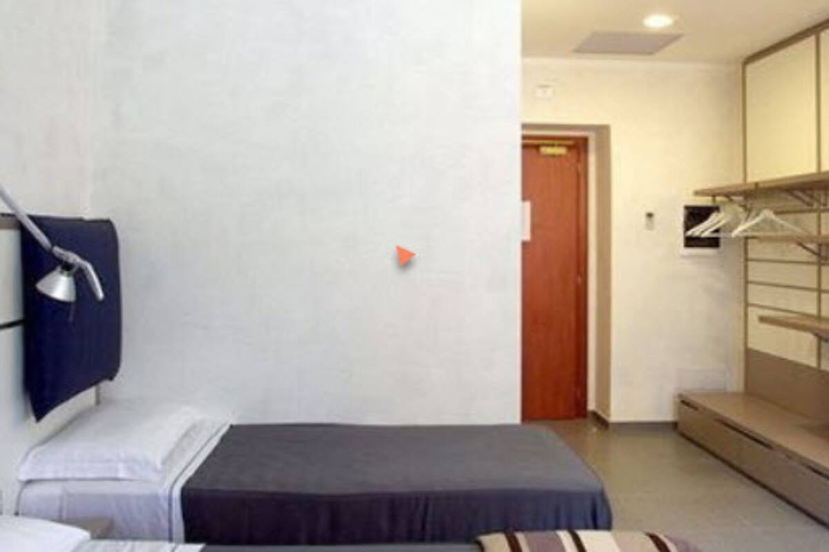 A small, neatly arranged bedroom with a bed, a desk, and a wardrobe.