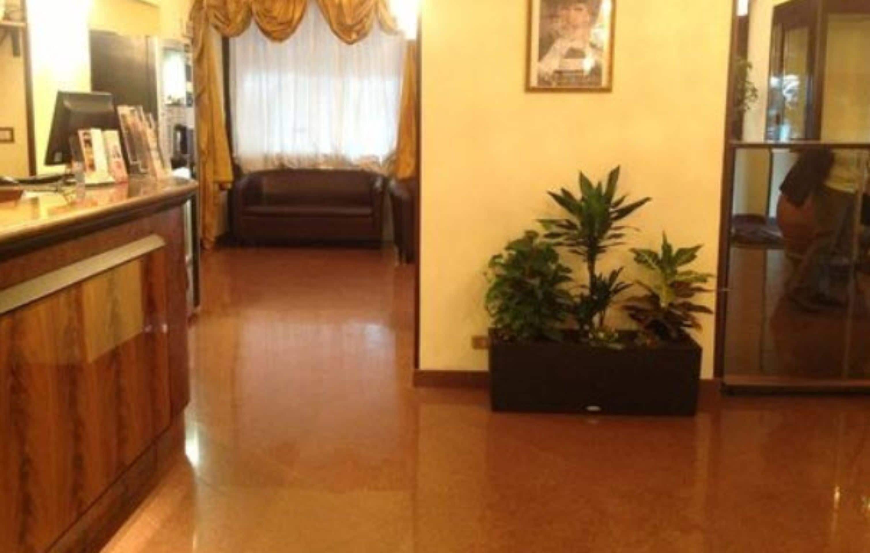 A hotel lobby with a reception desk, a sofa, and a potted plant.