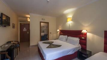 A hotel room with a bed, bedside tables, a desk, and a television.