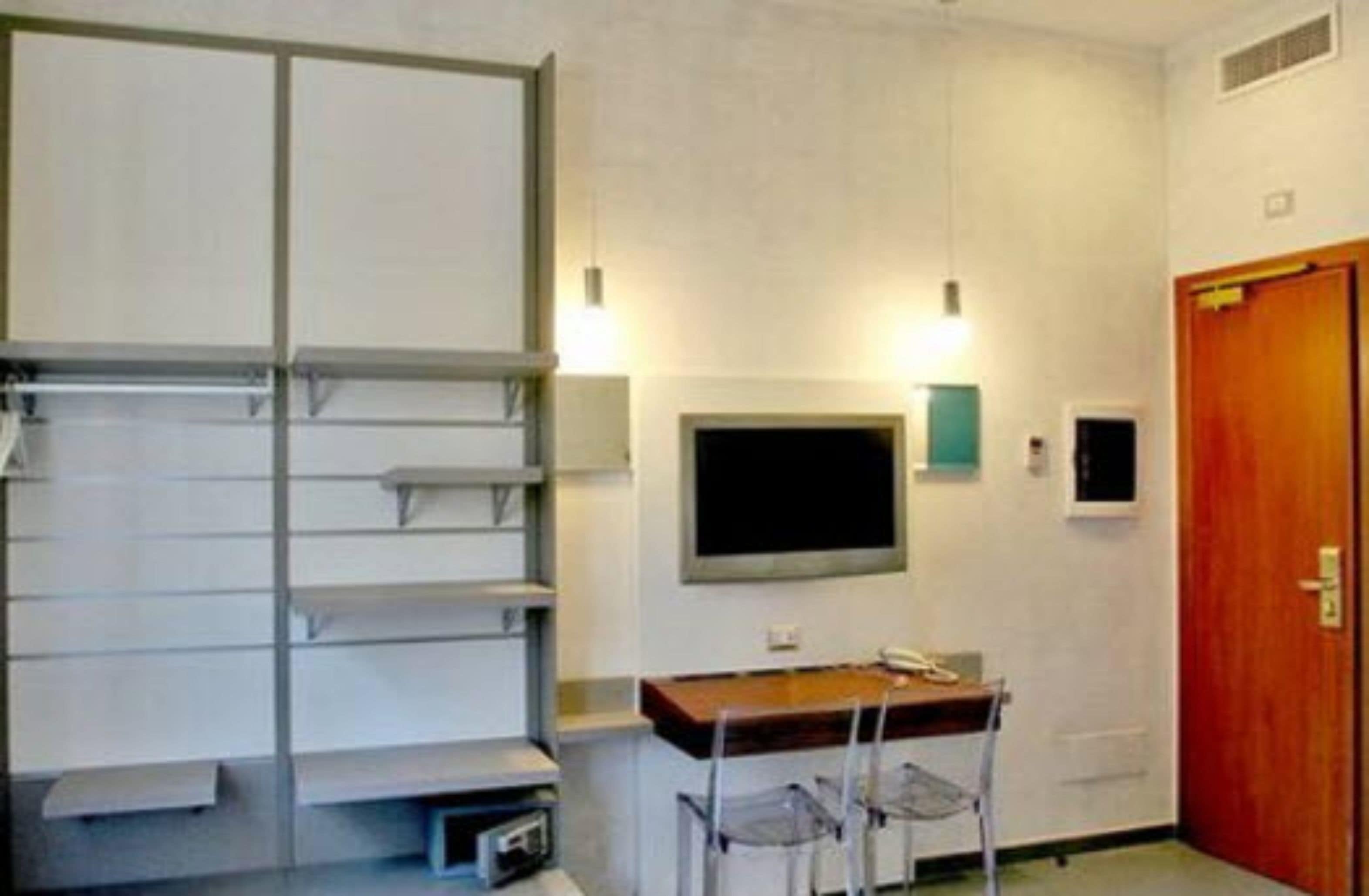 A room with a desk, chairs, a flat-screen TV, and a wooden door.