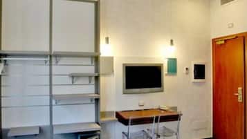 A room with a desk, chairs, a flat-screen TV, and a wooden door.