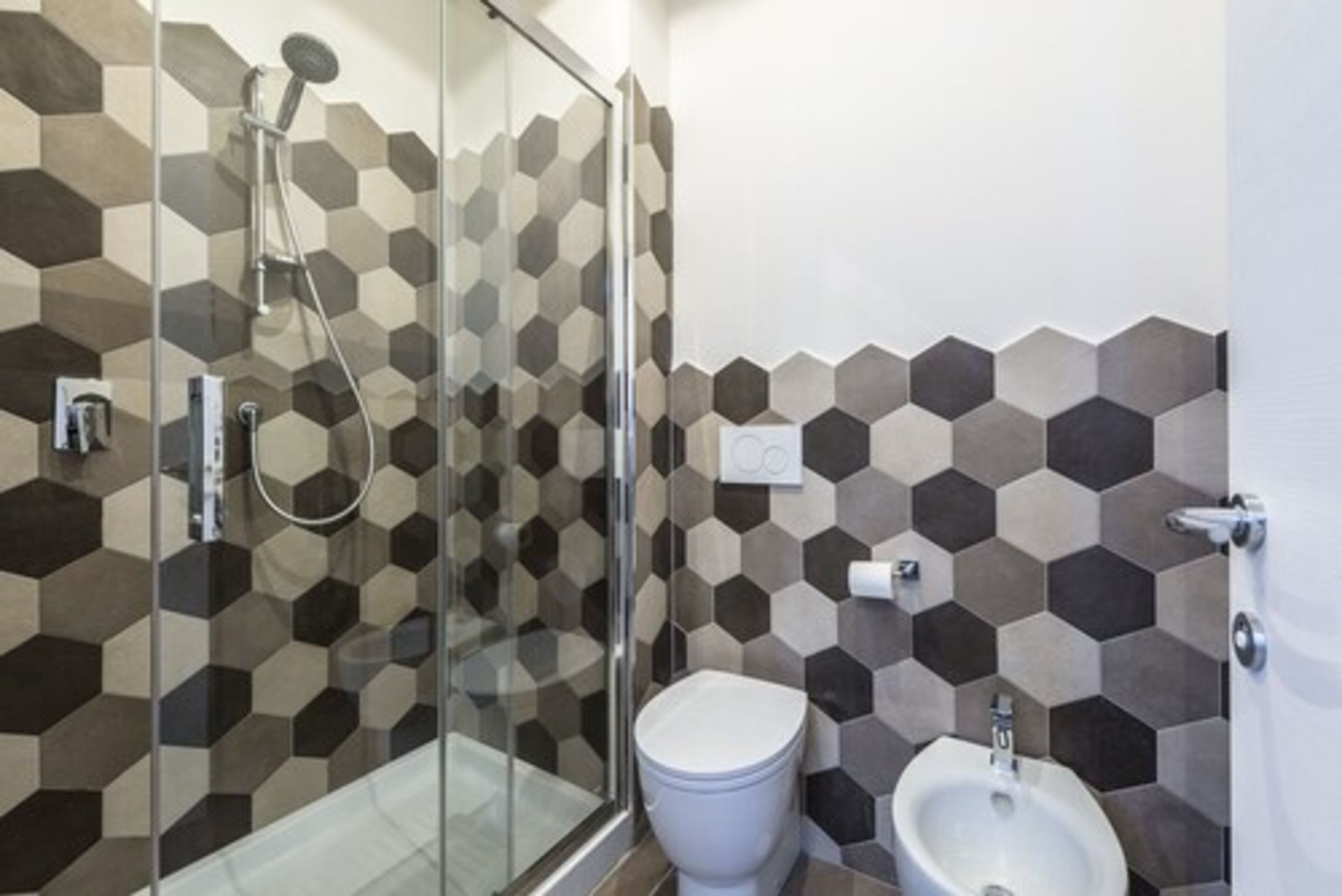 A modern bathroom with a glass shower enclosure, a toilet, and a bidet.
