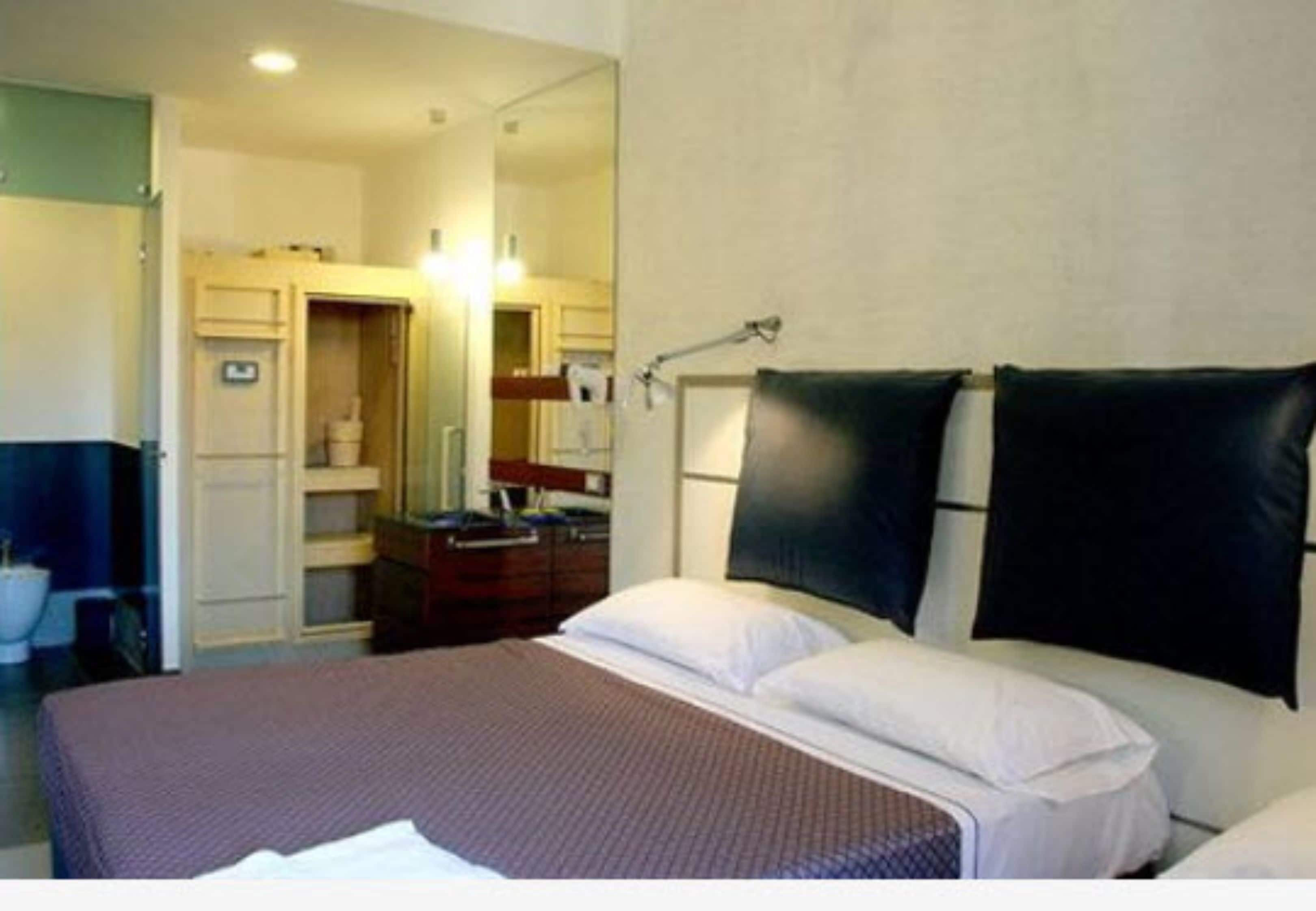 A hotel room with a bed, a desk, and a bathroom visible through an open door.