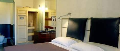 A hotel room with a bed, a desk, and a bathroom visible through an open door.