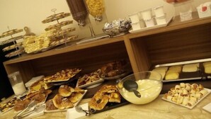 Ein reichhaltiges Buffet mit verschiedenen Speisen, darunter Gebäck, Früchte und eine Suppenschüssel.