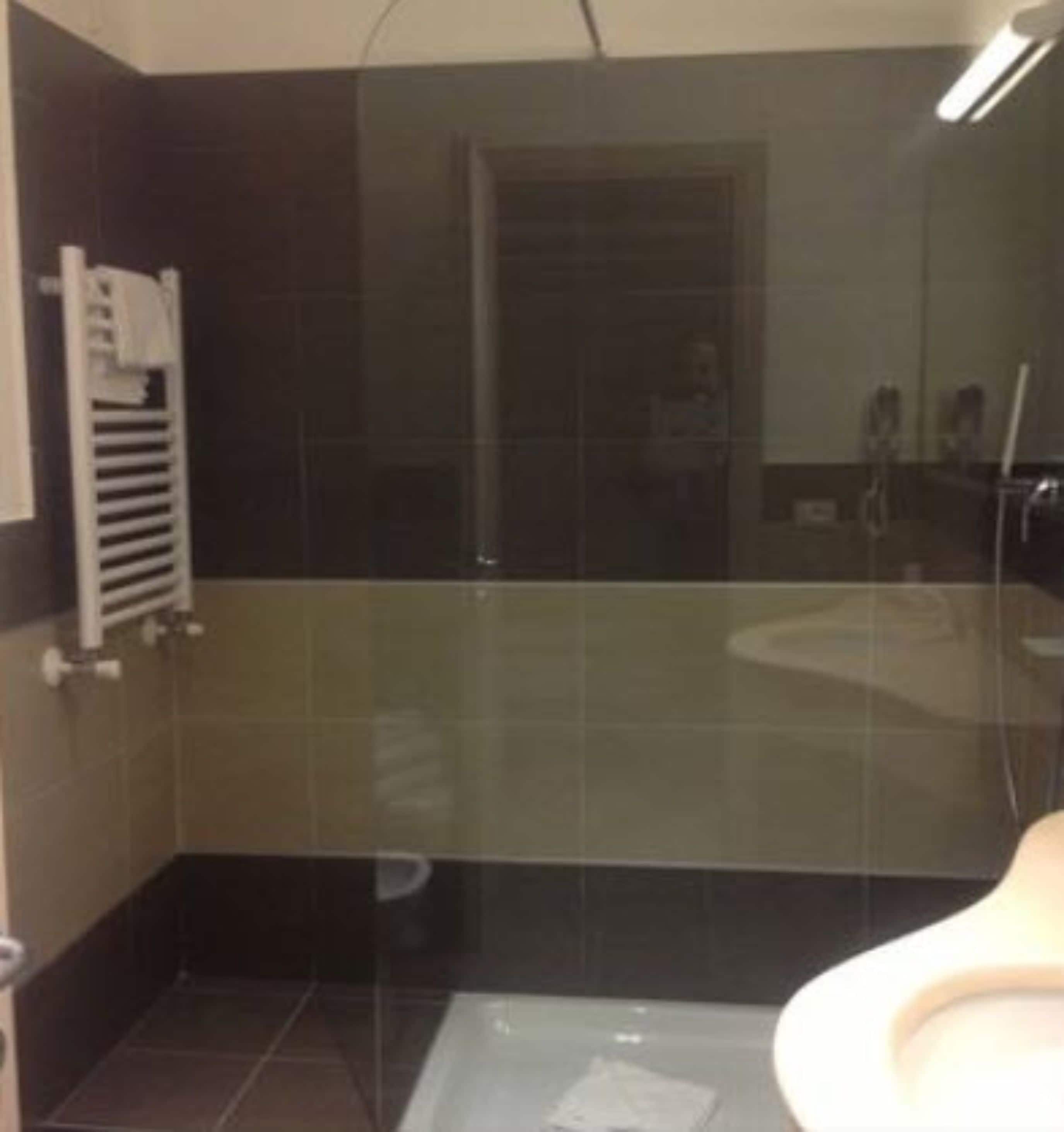 A bathroom with a glass shower enclosure, a white sink, and a towel rack.