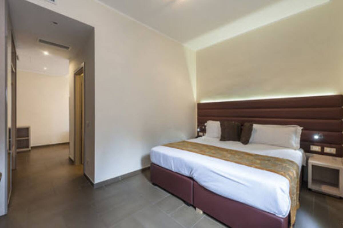 A hotel room with a large bed, a wooden headboard, a bedside table, and a nightstand.