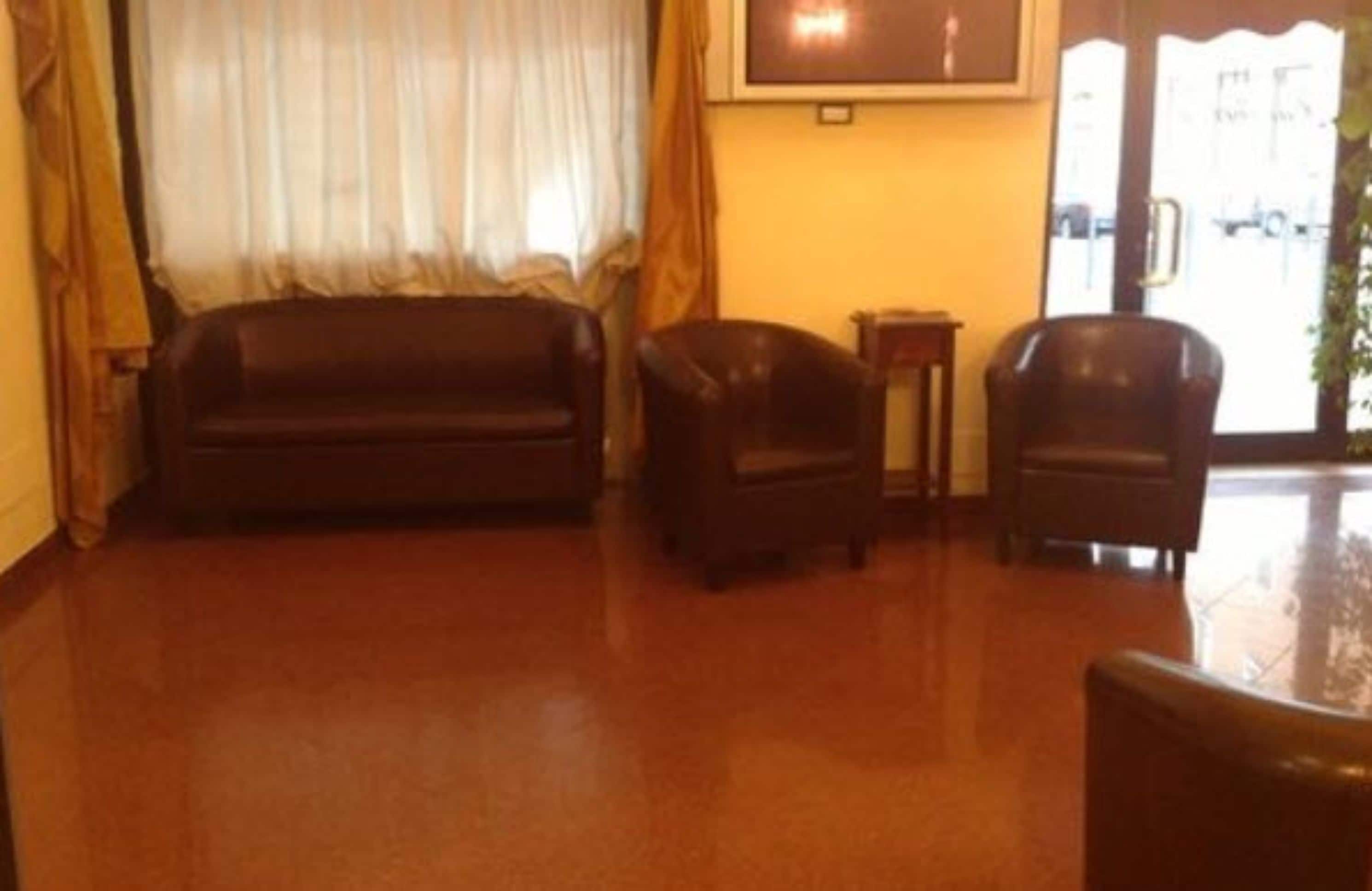 Una sala de estar con un sofá marrón oscuro, dos sillones y una mesita.
