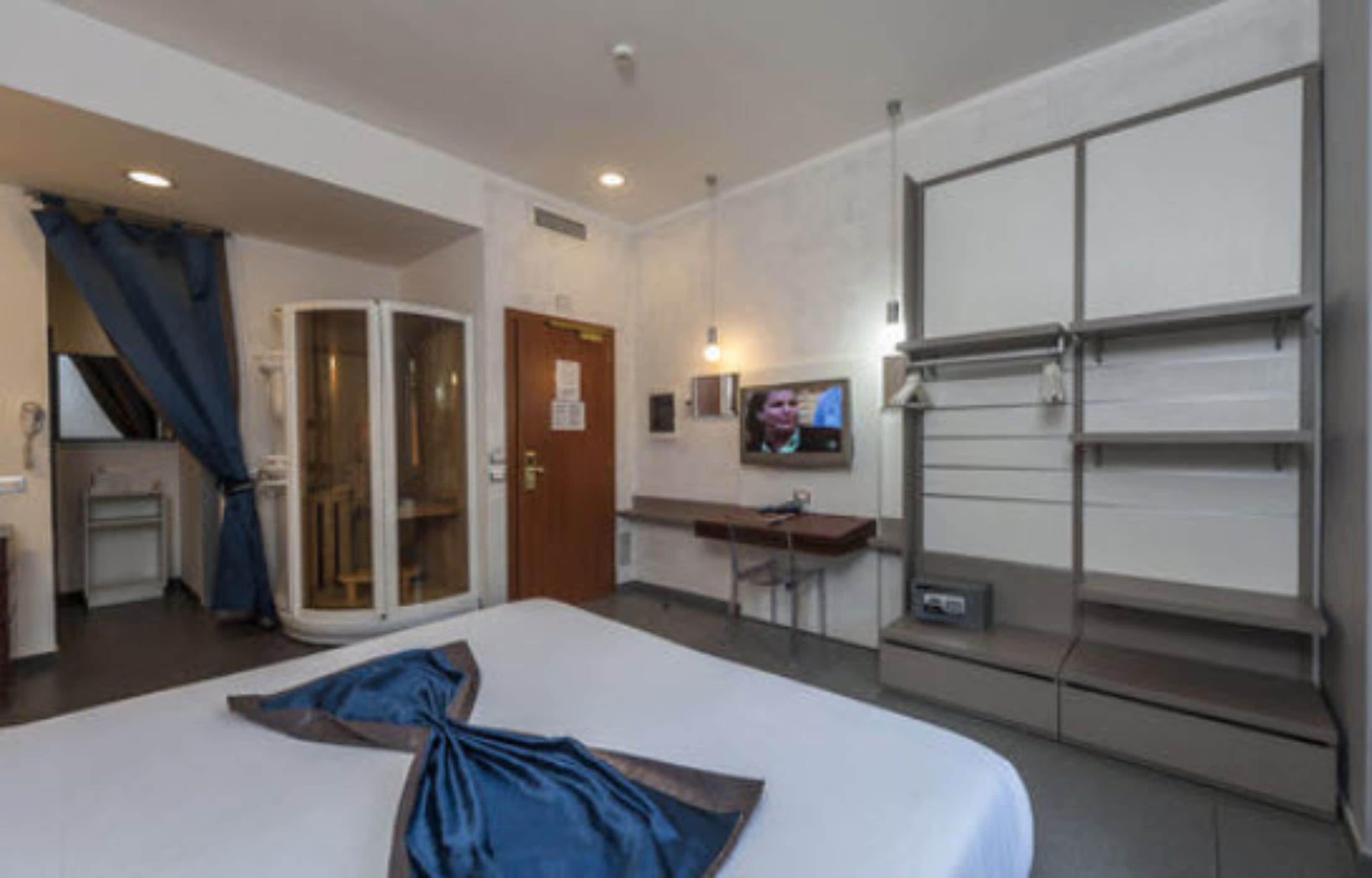 Una habitación de hotel con una cama, un escritorio, un televisor y un divisor corredizo.