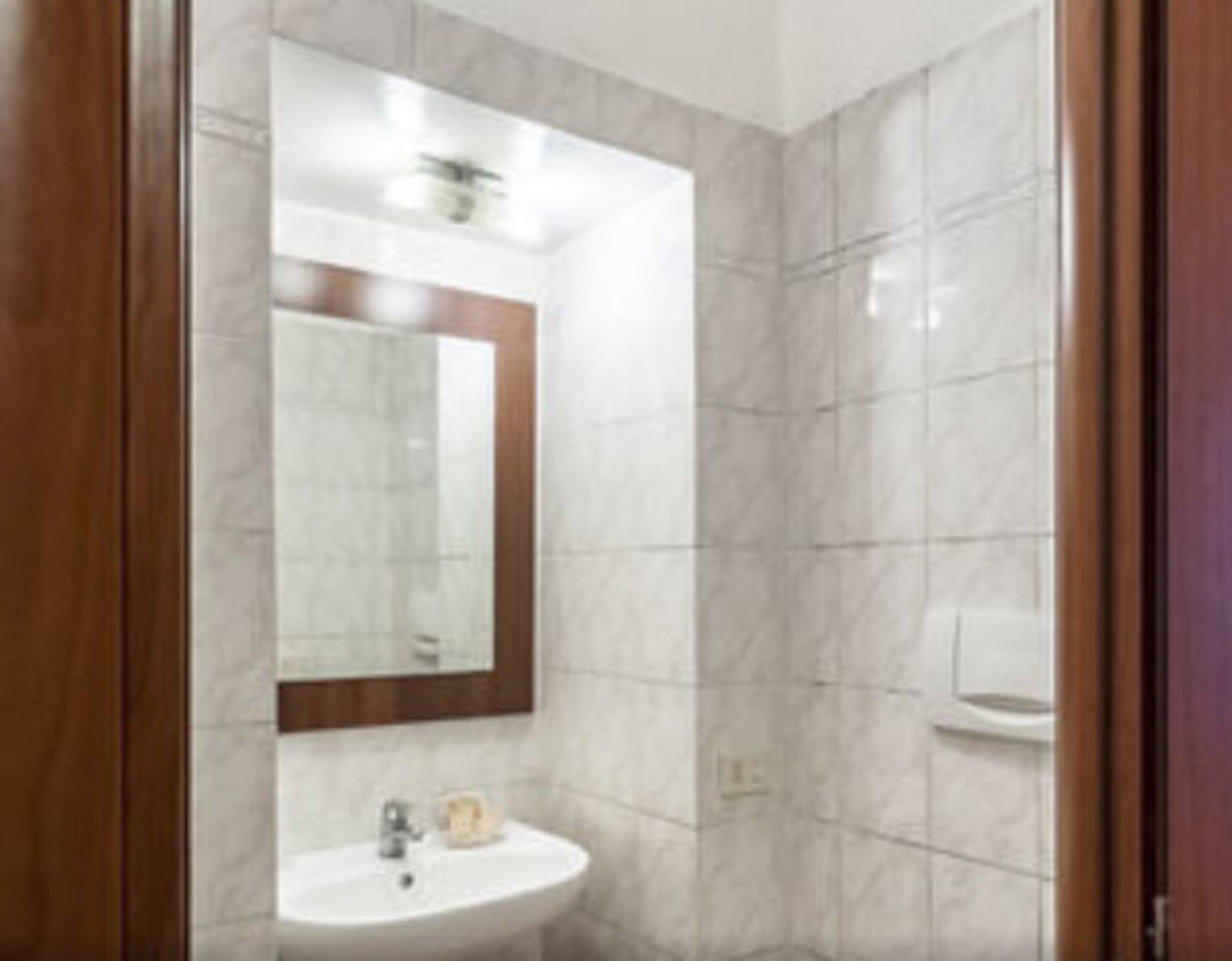 A bathroom with a white sink, a mirror, and a toilet.