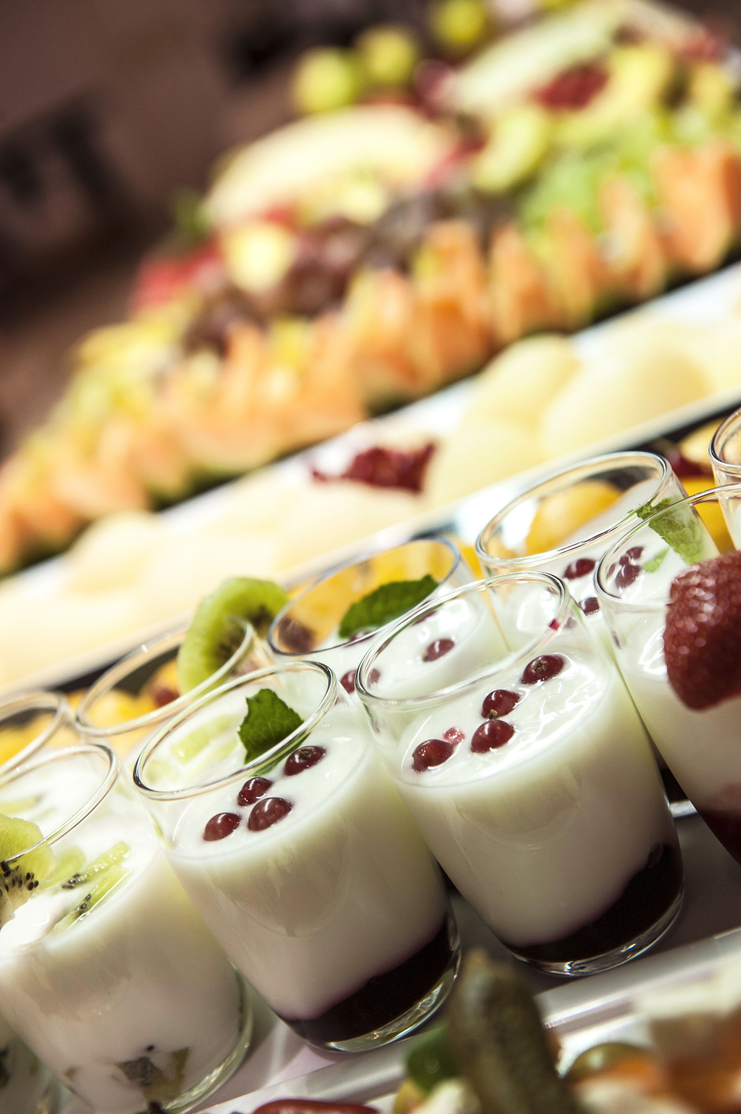 Ein Dessertbuffet mit verschiedenen joghurtbasierten Getränken mit Früchten und einer Auswahl weiterer Desserts im Hintergrund.