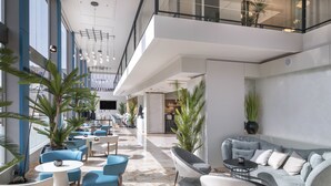 Un espacio interior moderno con una zona de estar que incluye sofás, sillas, una mesa de centro y plantas en macetas.