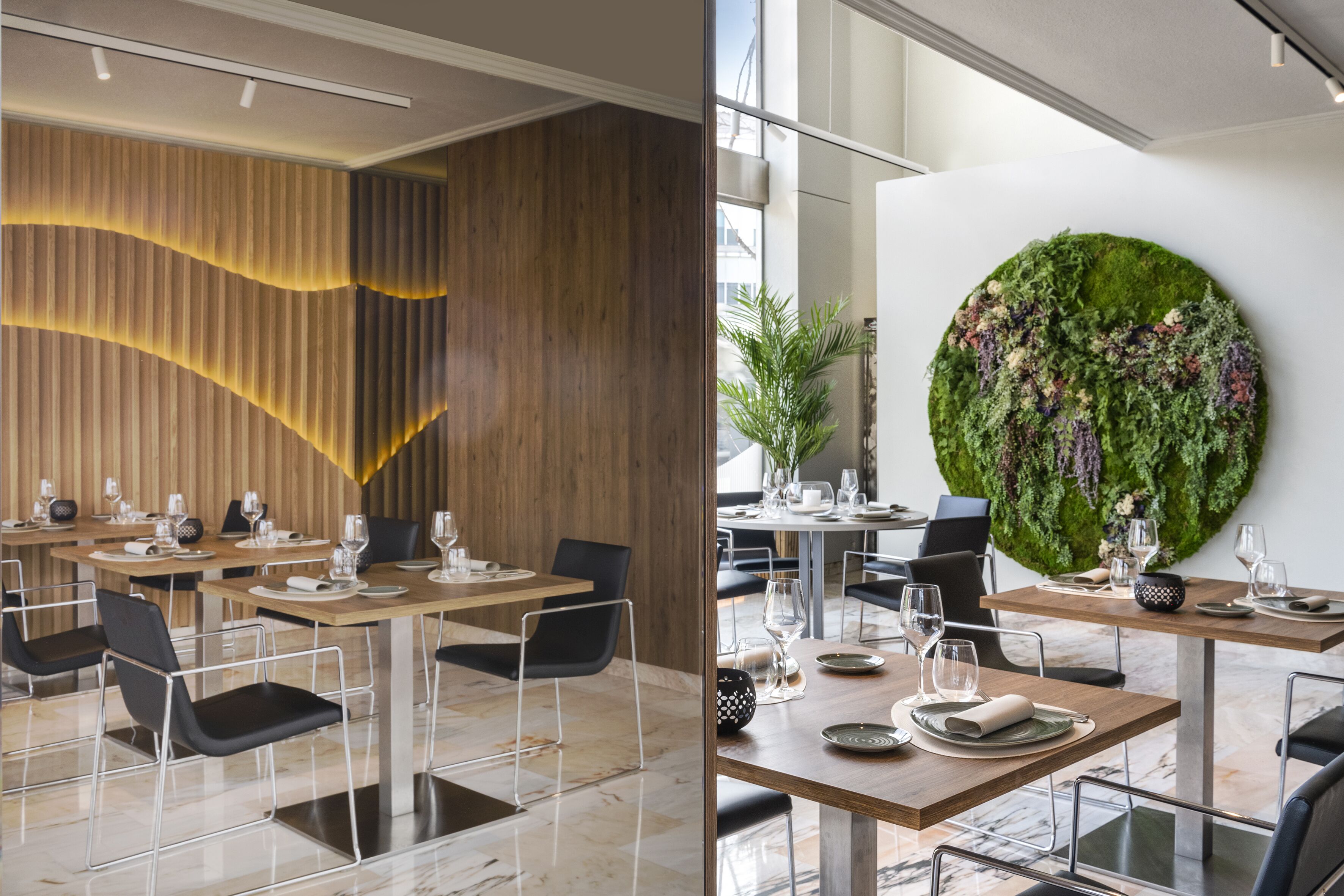 En modern restaurang med väggar beklädda med träpaneler, marmorgolv och ett stort konstverk i form av en grön vägg.