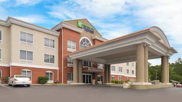 Un hotel Holiday Inn Express con entrada techada, fachada de ladrillo y estacionamiento.