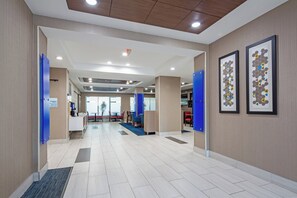 A hotel lobby with a reception desk, seating area, and artwork on the walls.